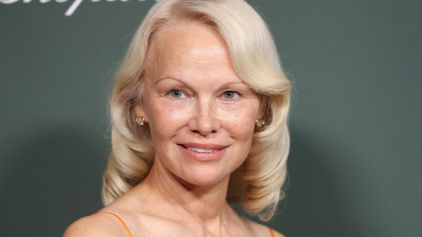 Pamela Anderson wears an orange dress with a sculpted '50s bob.